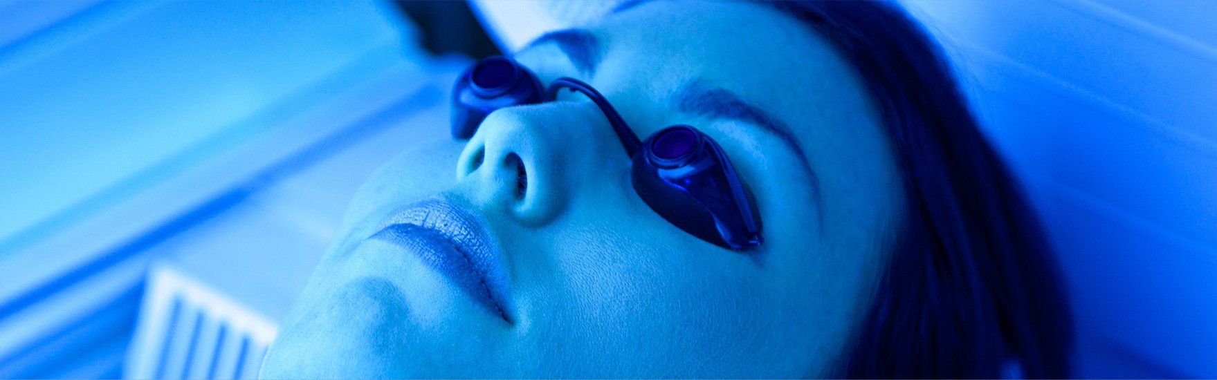 Une femme reçoit un traitement à la lumière bleue sur son visage.