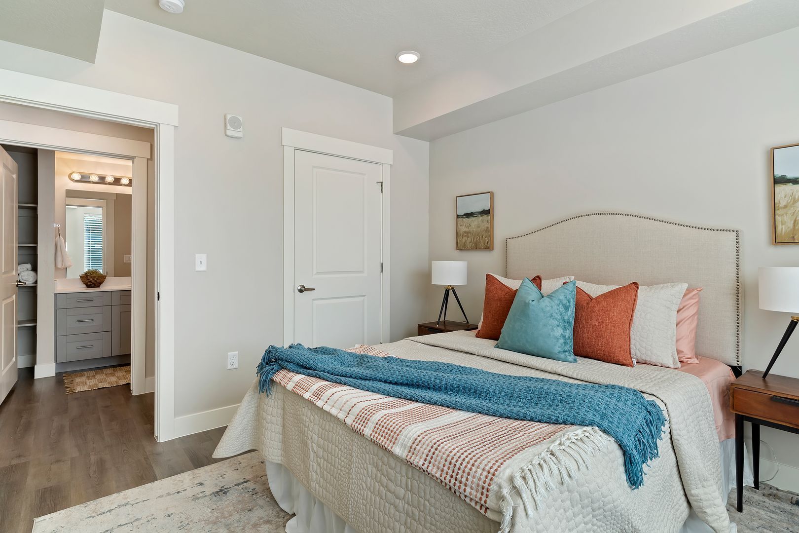 Bedroom with a bed, nightstands, and a door to a bathroom. Decorated with colorful pillows and a blue throw.