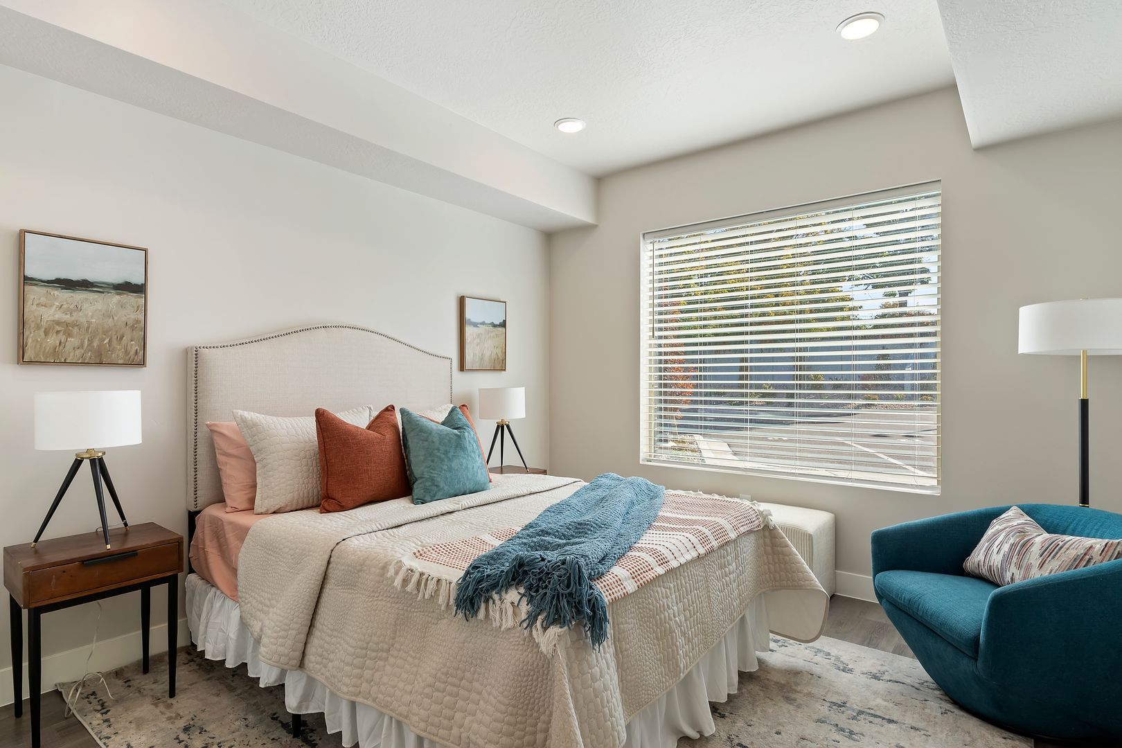 Bedroom with bed, nightstand, armchair, and window with blinds.