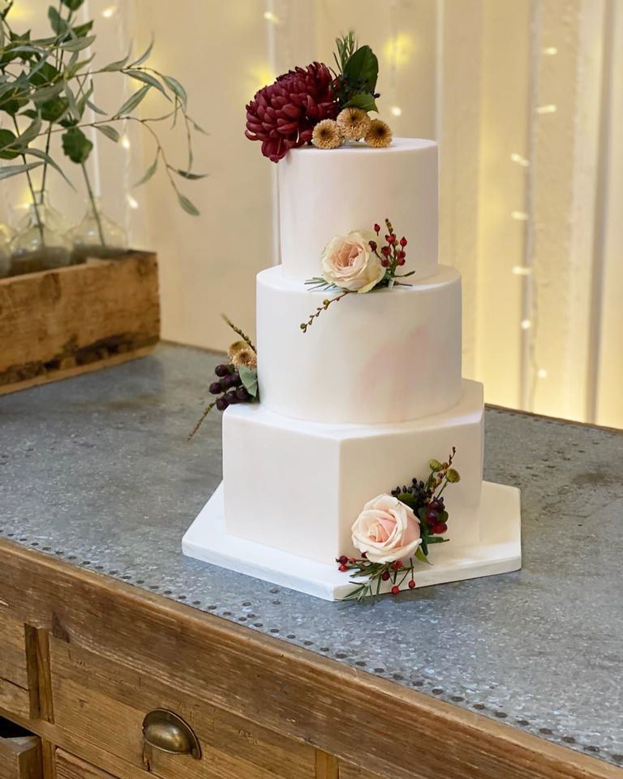 A white wedding cake is sitting on top of a wooden table.