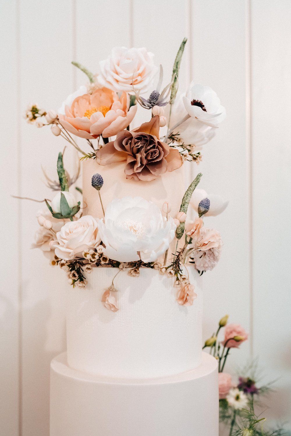 A white wedding cake with flowers on top of it.