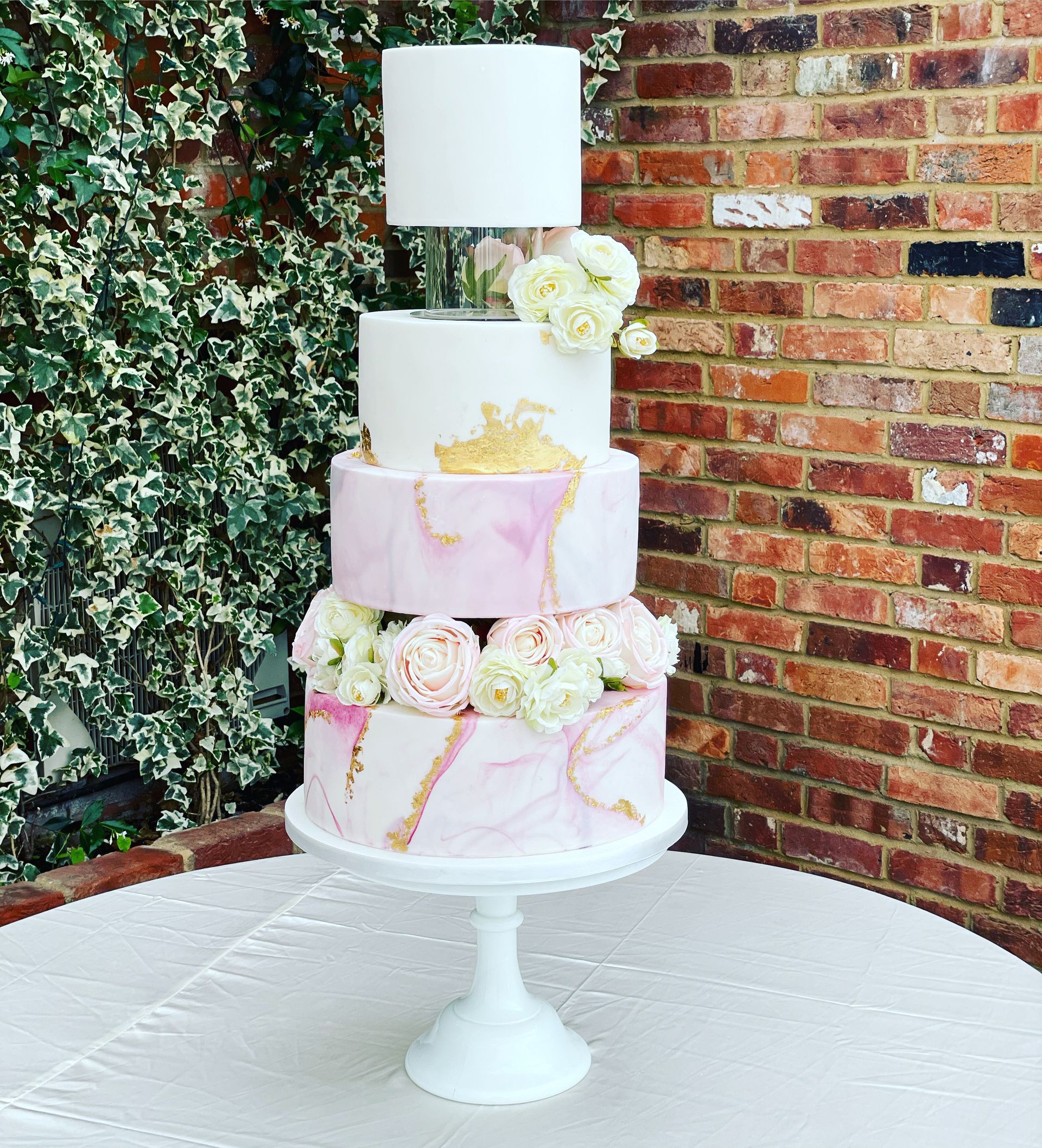 A wedding cake is sitting on a table in front of a brick wall.