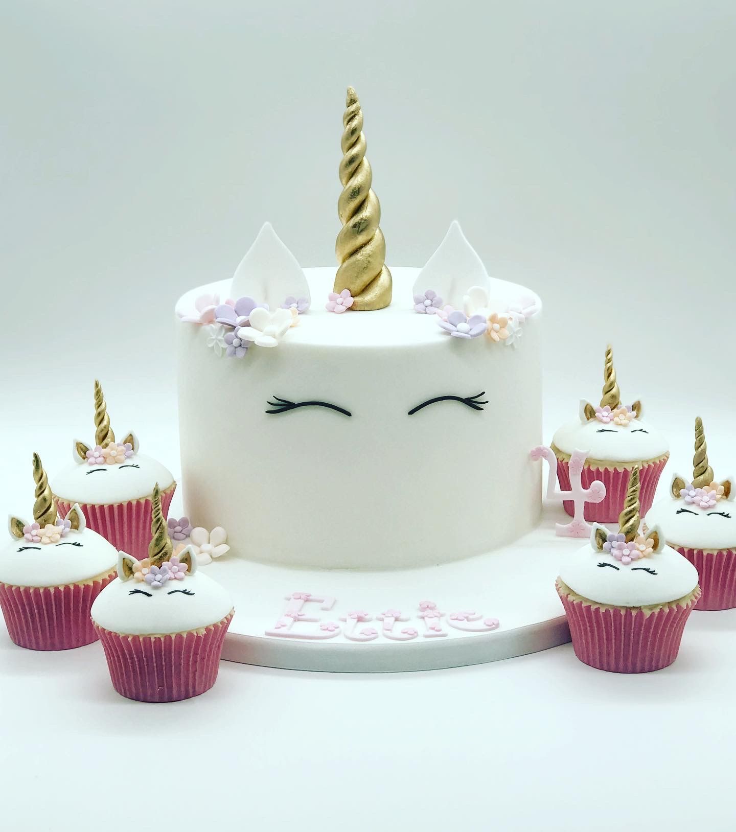 A unicorn cake and cupcakes are on a table