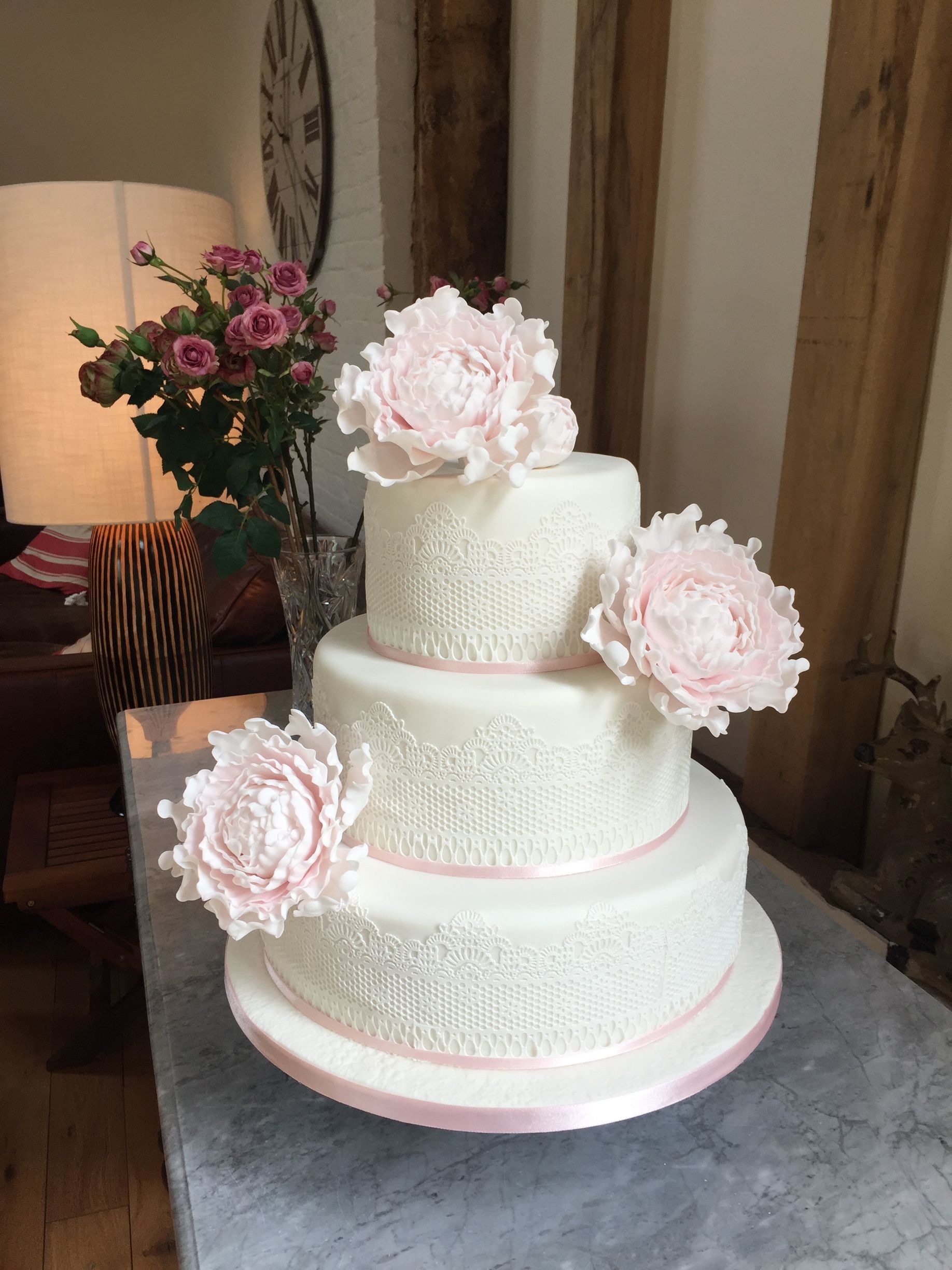A white wedding cake with pink flowers is sitting on a table.