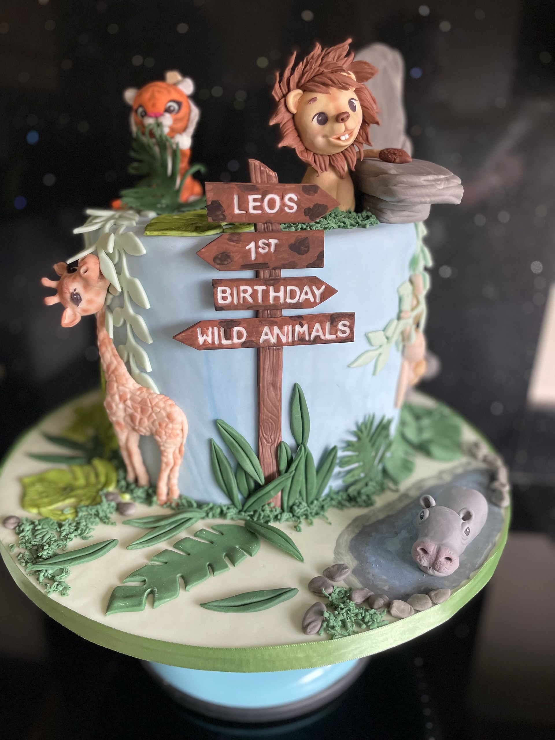 A birthday cake with a lion , giraffe , and hippo on it
