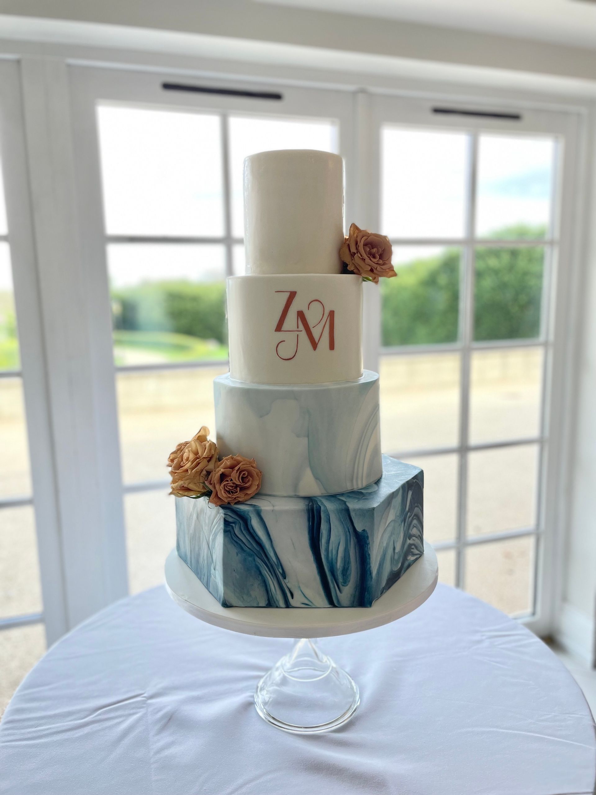 A wedding cake is sitting on a table in front of a window.