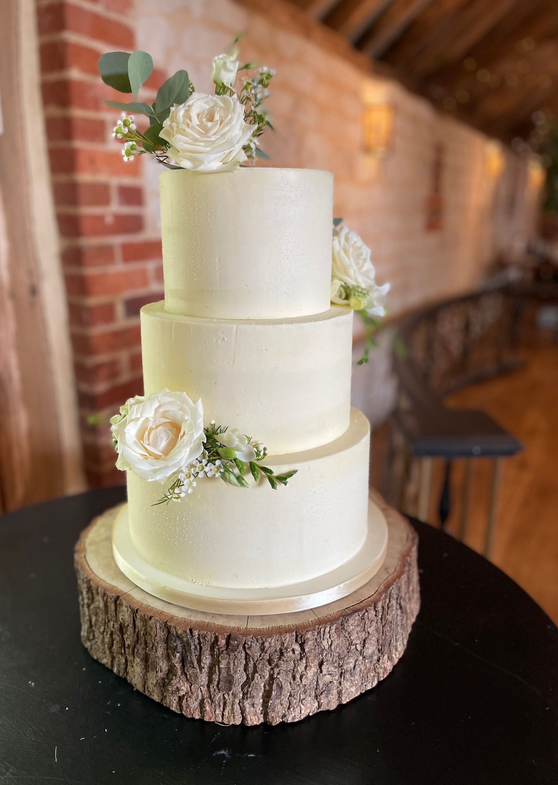 A wedding cake is sitting on top of a wooden stump on a table.