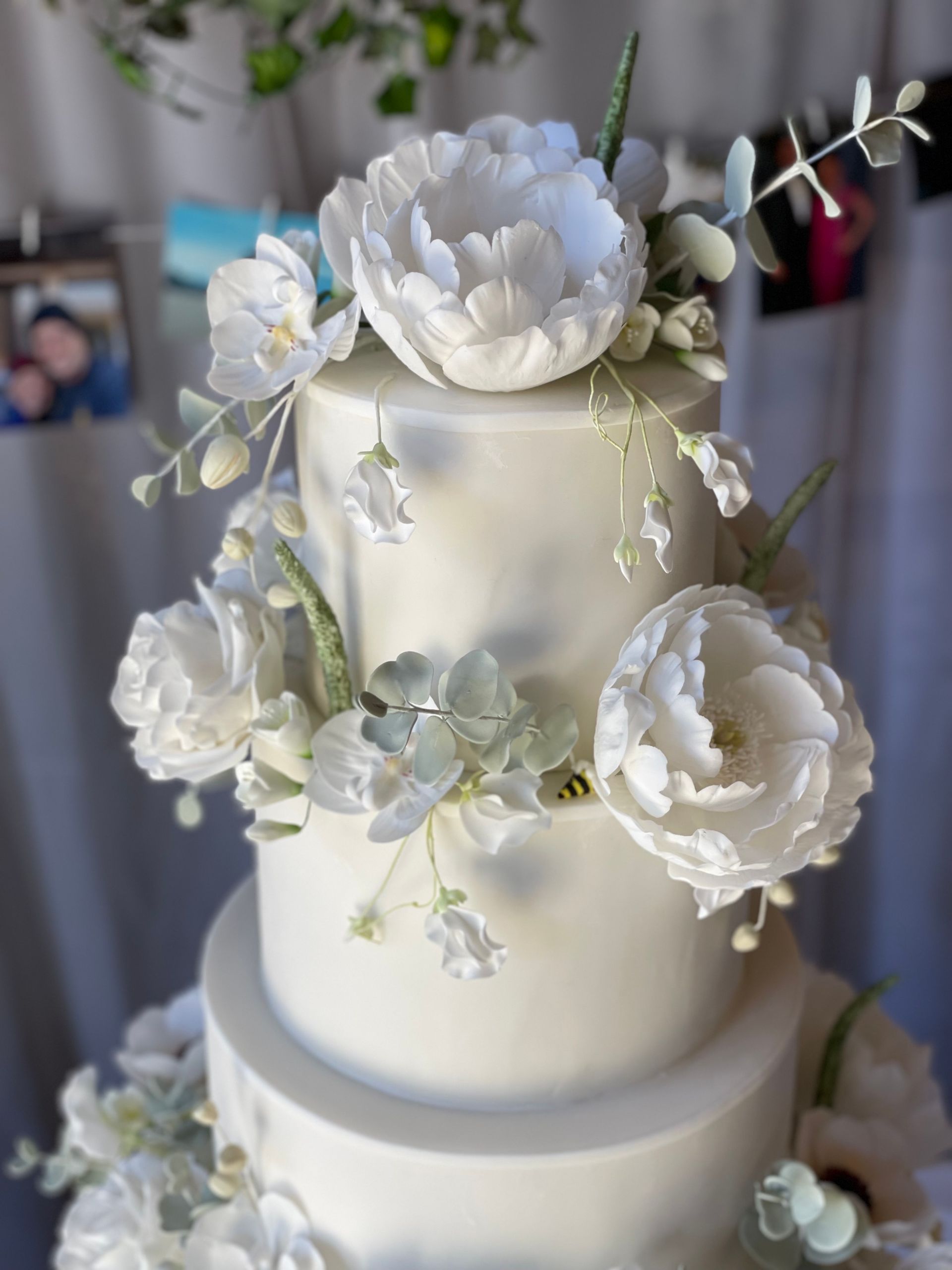A white wedding cake with white flowers on it is on a table.
