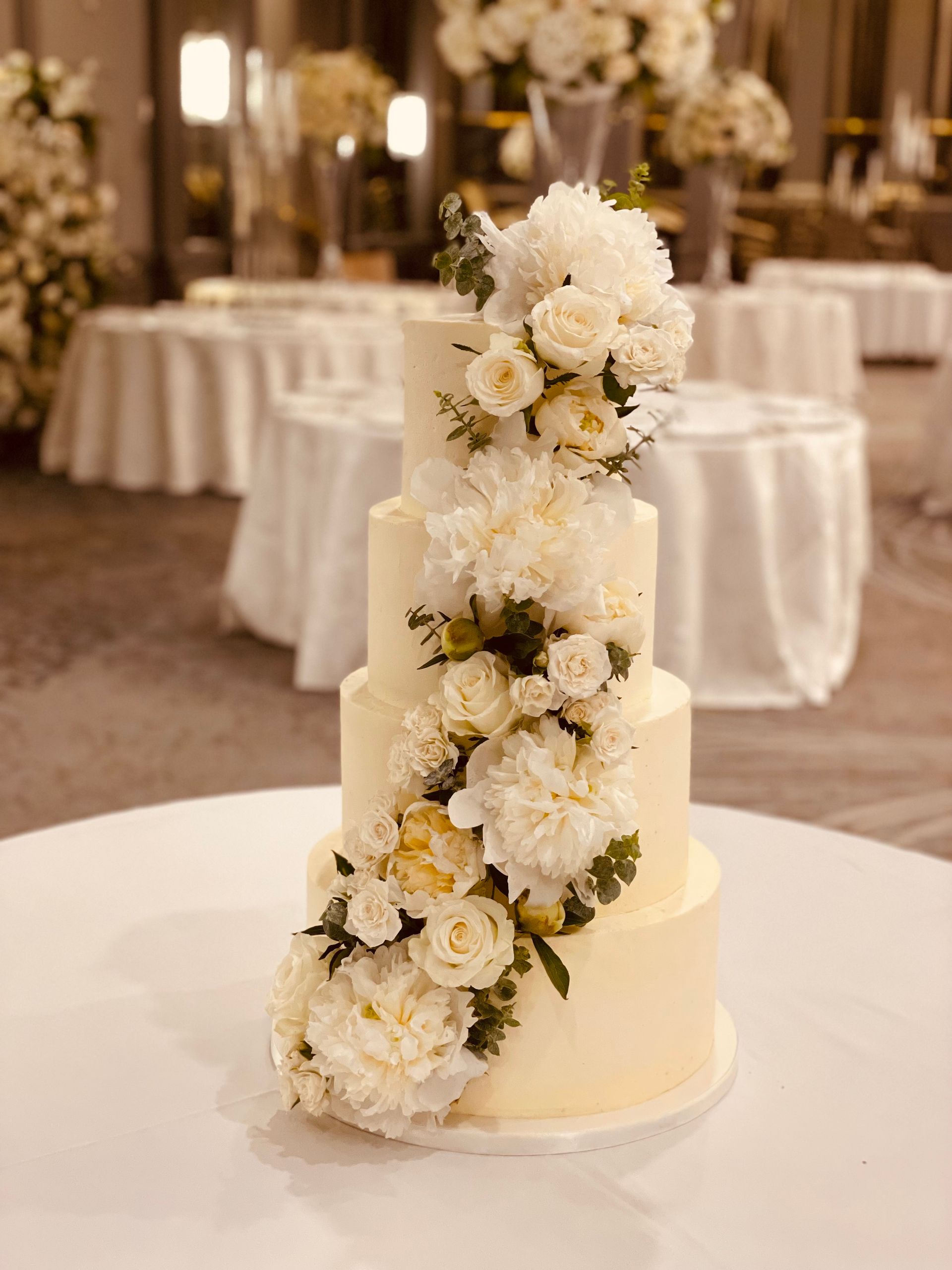 A wedding cake with white flowers on it is sitting on a table.