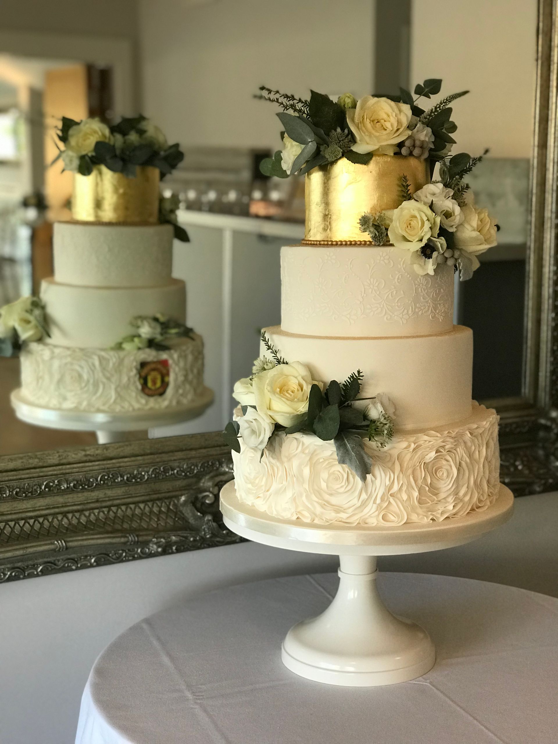 A wedding cake is sitting on a table in front of a mirror.