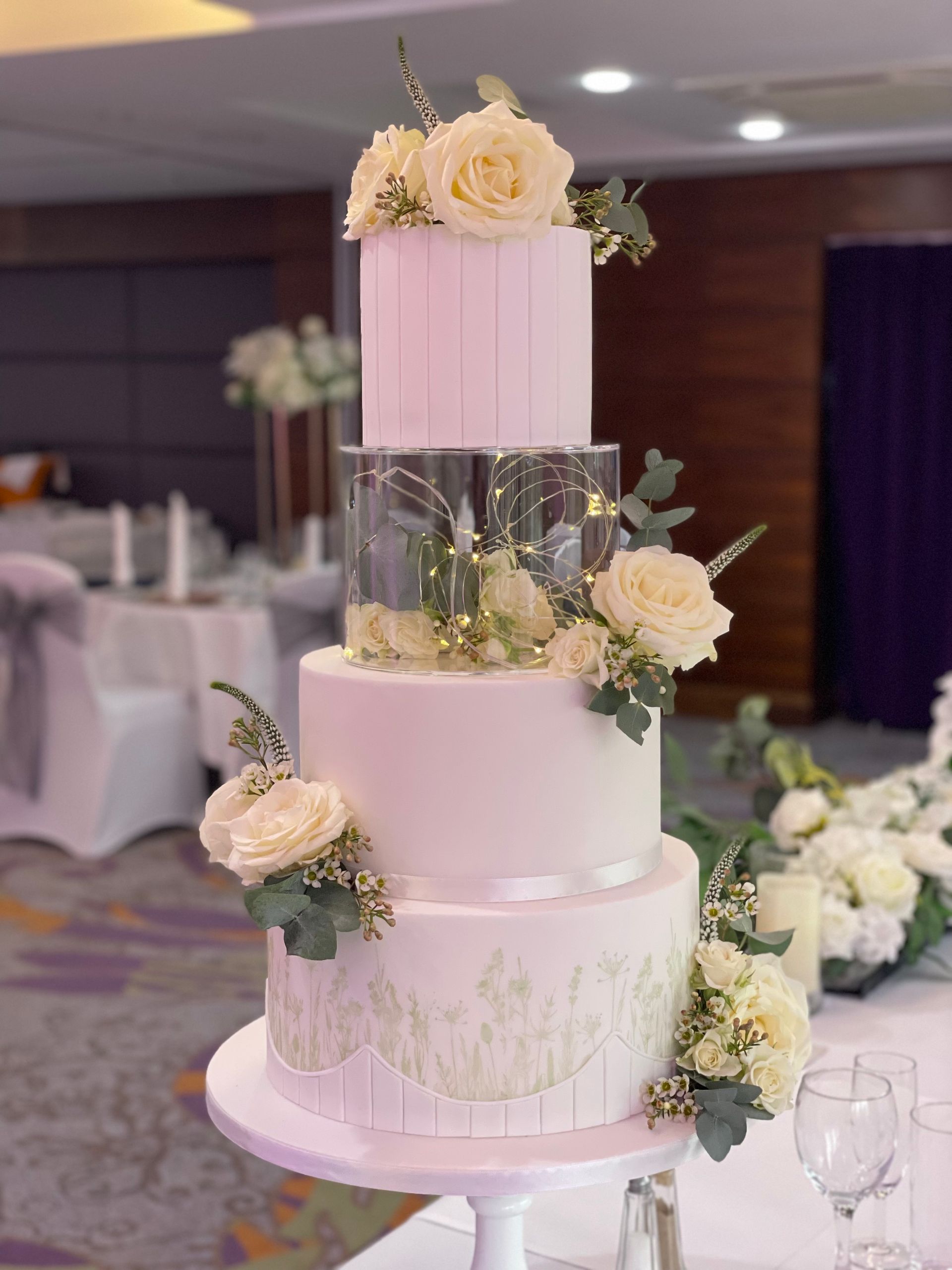A wedding cake is sitting on top of a table in a room.