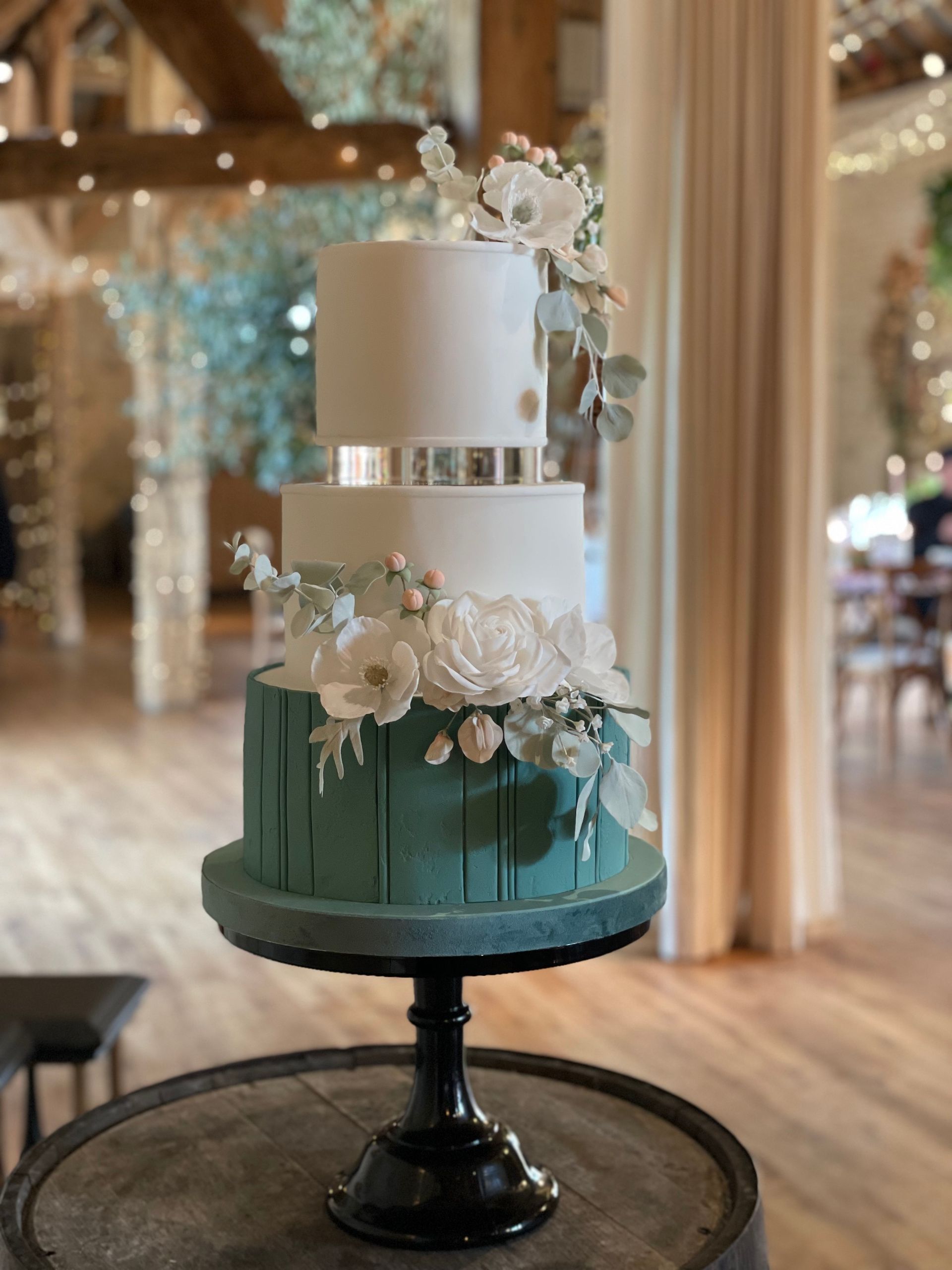 A wedding cake is sitting on top of a wooden barrel on a table.