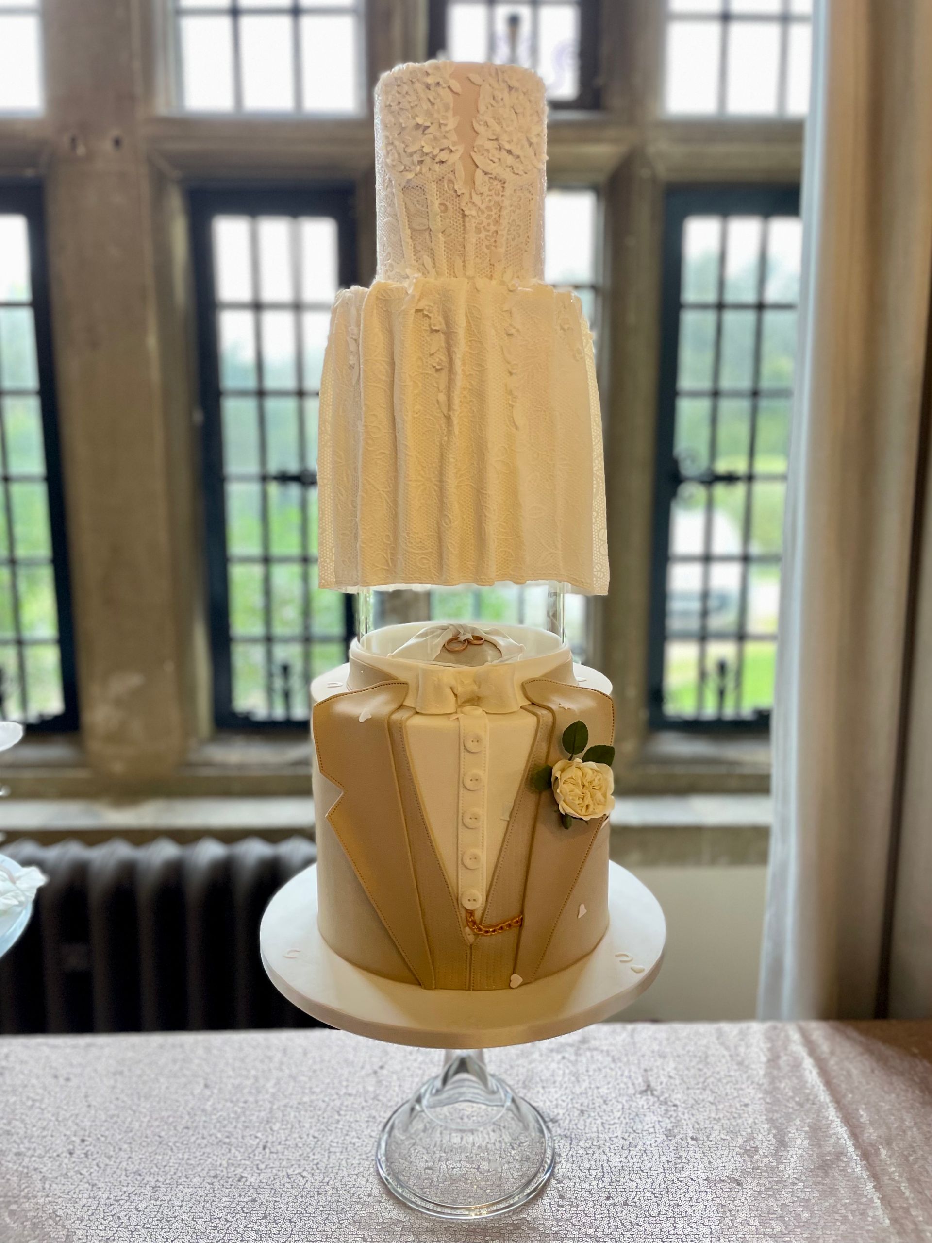 A wedding cake is sitting on a table in front of a window.