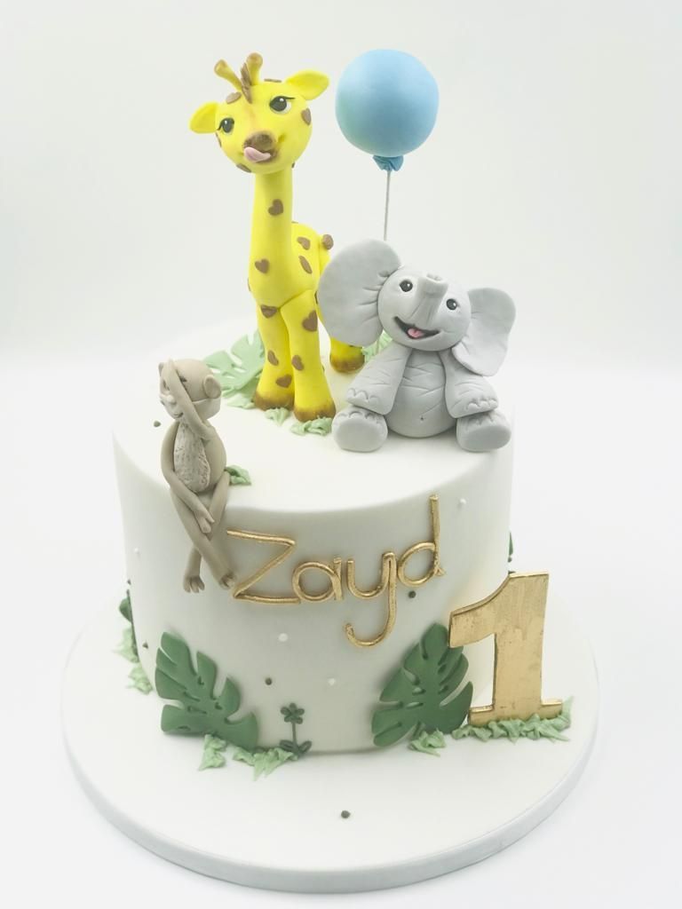 A birthday cake with a giraffe, elephant and monkey on it