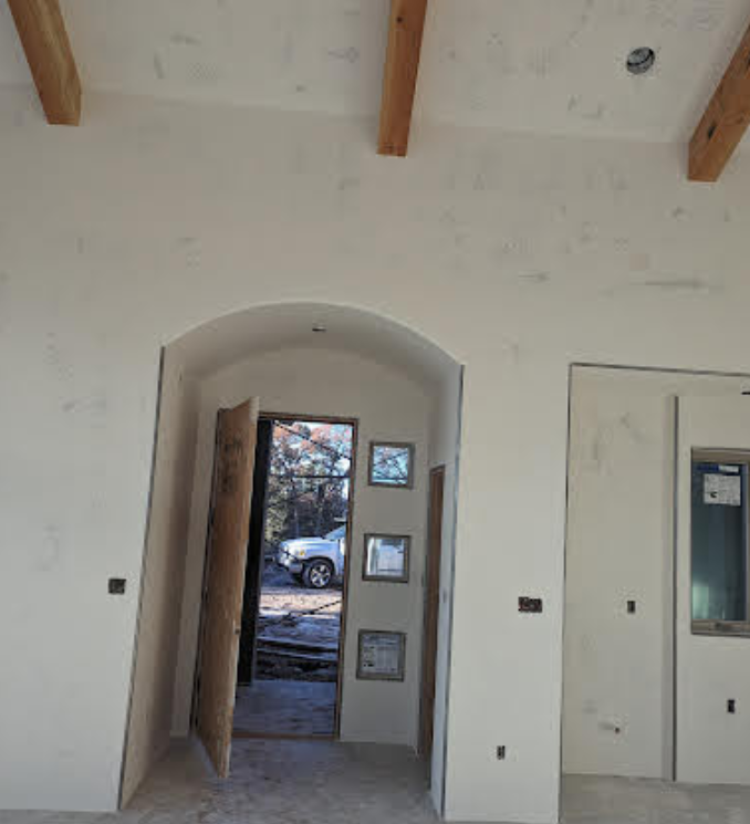 A car is parked in the backyard of a house under construction