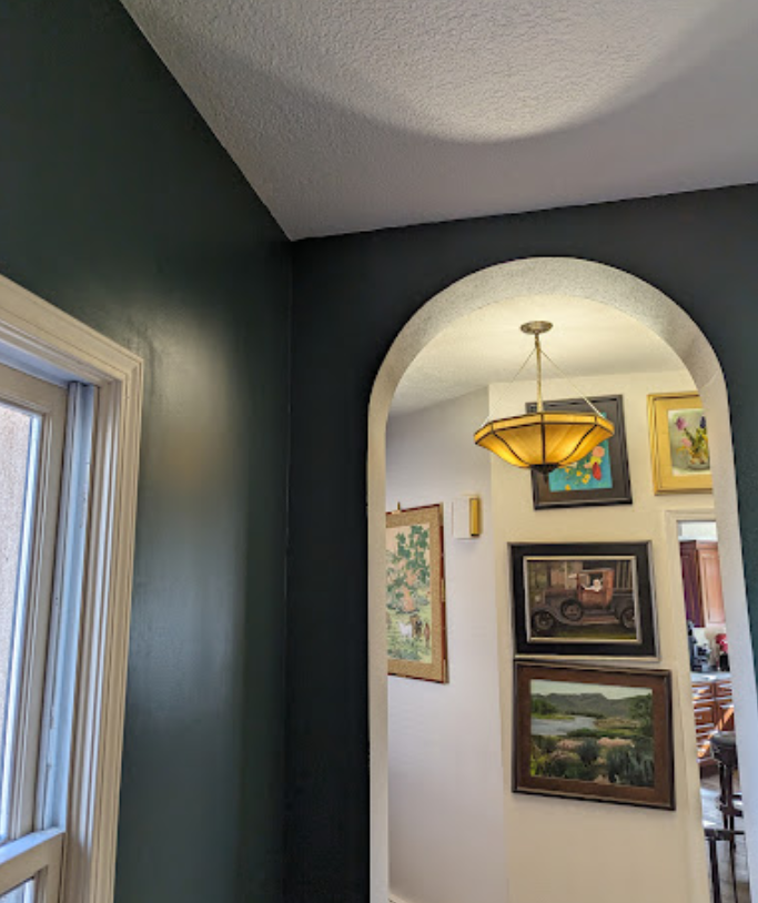 A hallway with a ceiling light and paintings on the wall