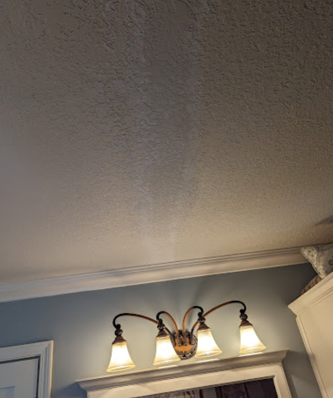 A bathroom vanity light is hanging from the ceiling in a bathroom.