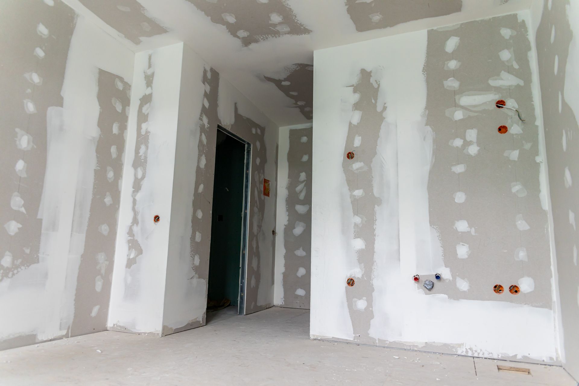 An empty room with drywall walls and a door.