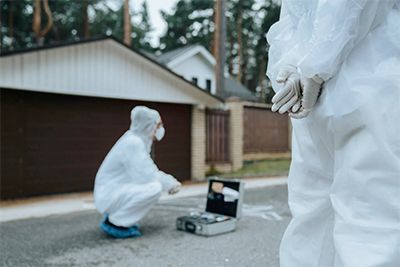 A couple of people in protective suits are standing in front of a house.