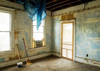 An empty room with a broom and bucket in it.