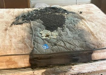 A dirty mattress is sitting on top of a wooden table.