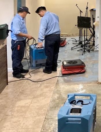 Two men are working on a machine in a room.