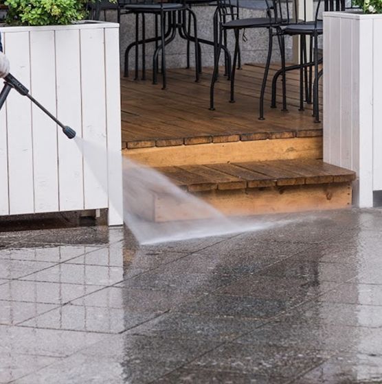 A person is using a high pressure washer to clean a patio.