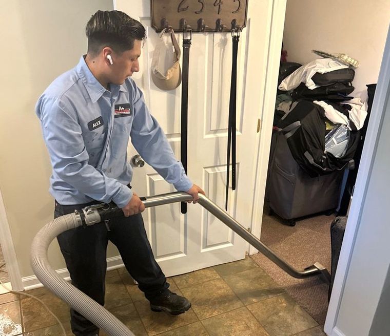 A man is using a vacuum cleaner to clean a hallway.