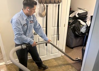 A man is using a vacuum cleaner in a hallway.