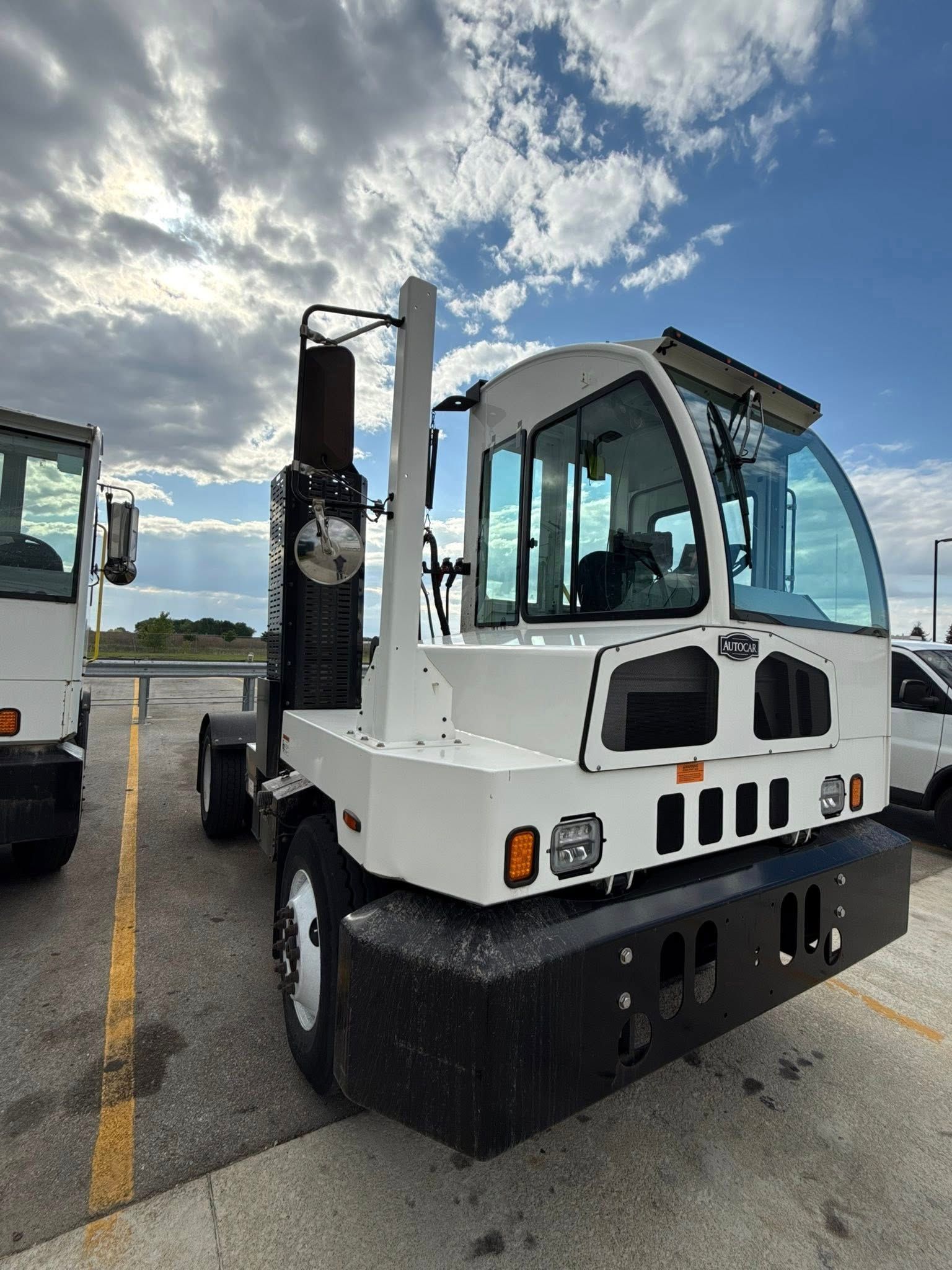 A white truck is parked next to a black truck in a parking lot.