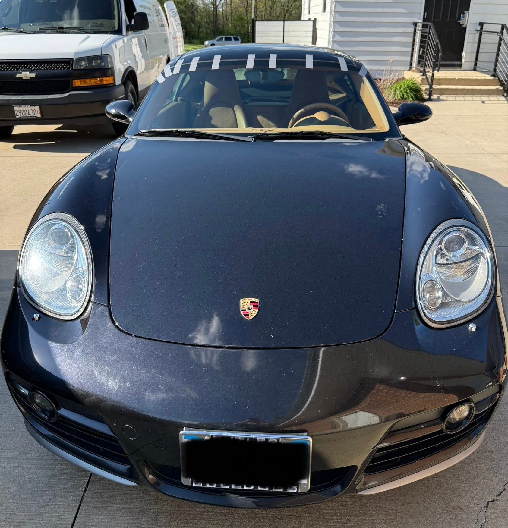 A black porsche is parked in a parking lot