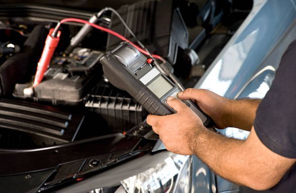 Mechanic using a diagnostic tool on a car engine, red and black cables attached | G&R Auto Corp