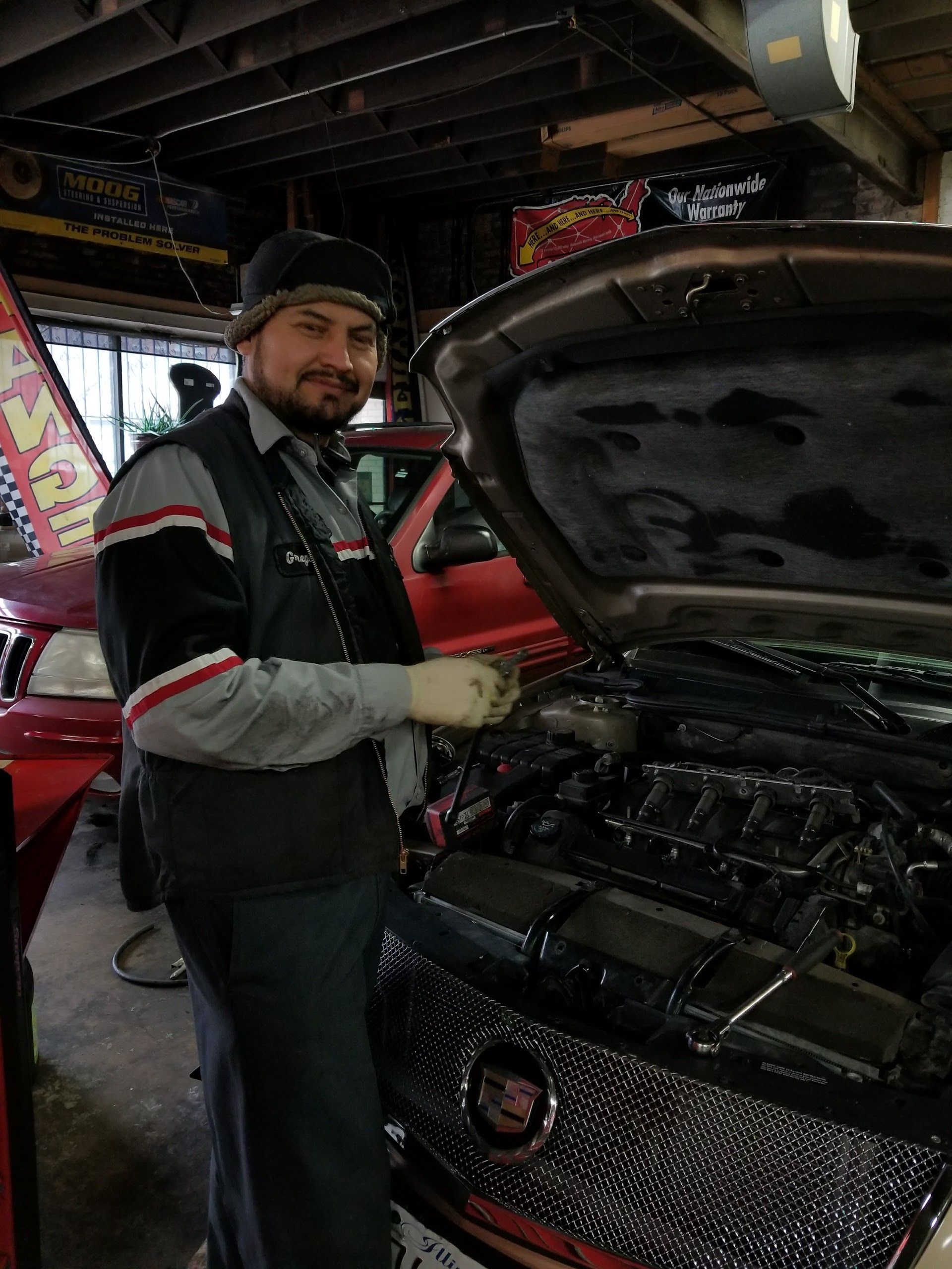 Mechanic checking a car engine, wearing uniform with red trim | G&R Auto Corp