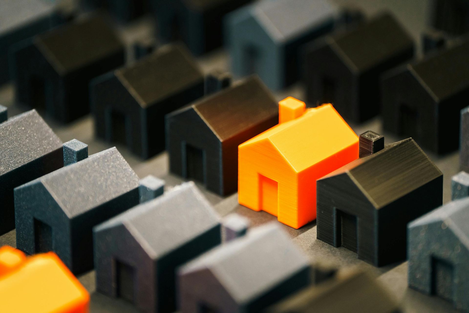 Black and orange miniature house blocks arranged in a grid, with one bright orange house standing out