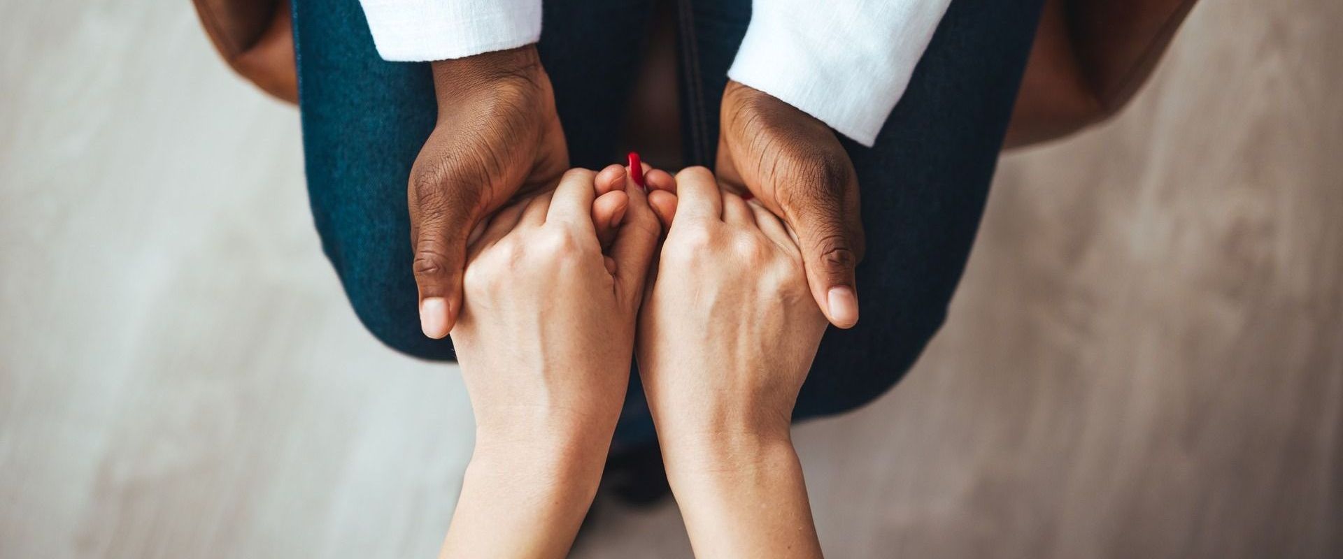 A man and a woman are holding hands while sitting on the floor.