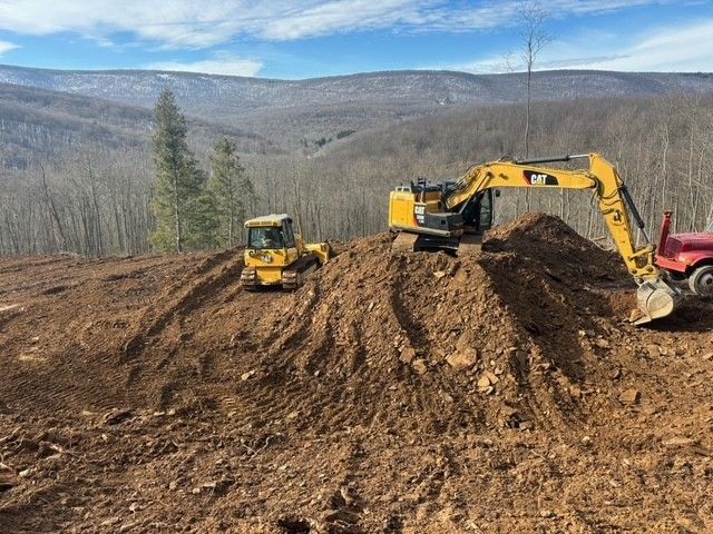Truck being loaded with concrete cylinders by an excavator, construction site.