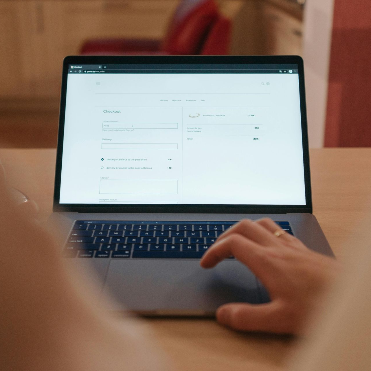 Person using laptop on wooden desk, interface visible on screen.