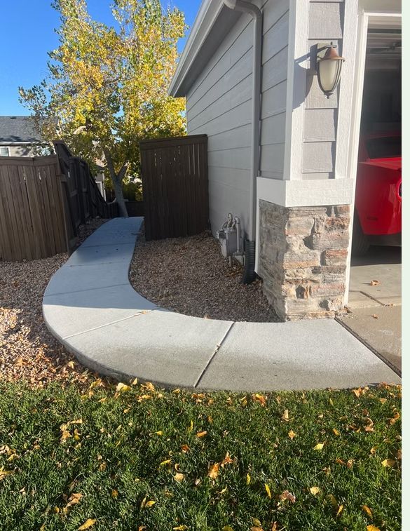 Curving concrete walkway leads to a house with a stone-covered column and garage.