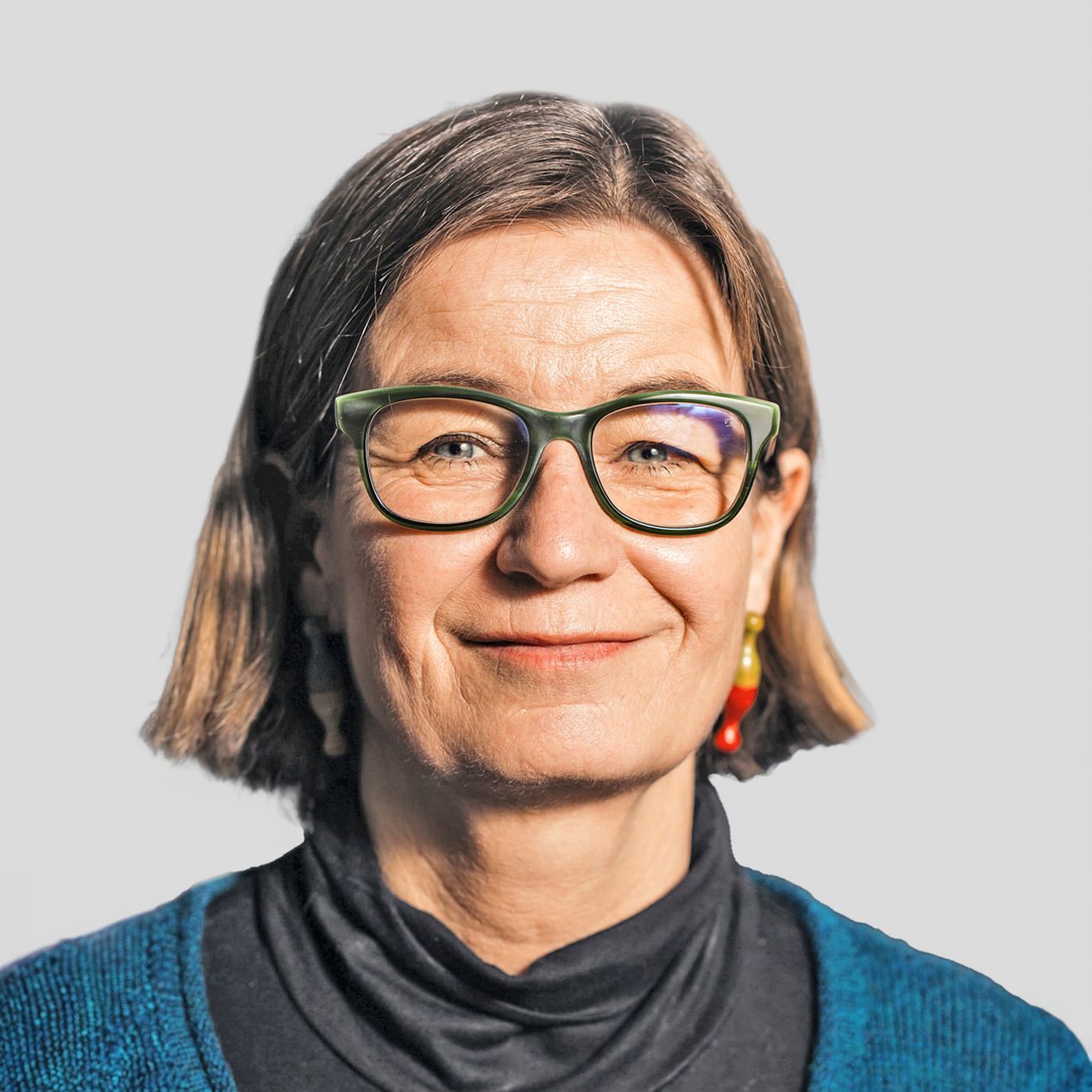 Porträtfoto von Barbara Herold, Jurorin, mit Brille und kurzem, schulterlangem Haar vor neutralem Hintergrund.