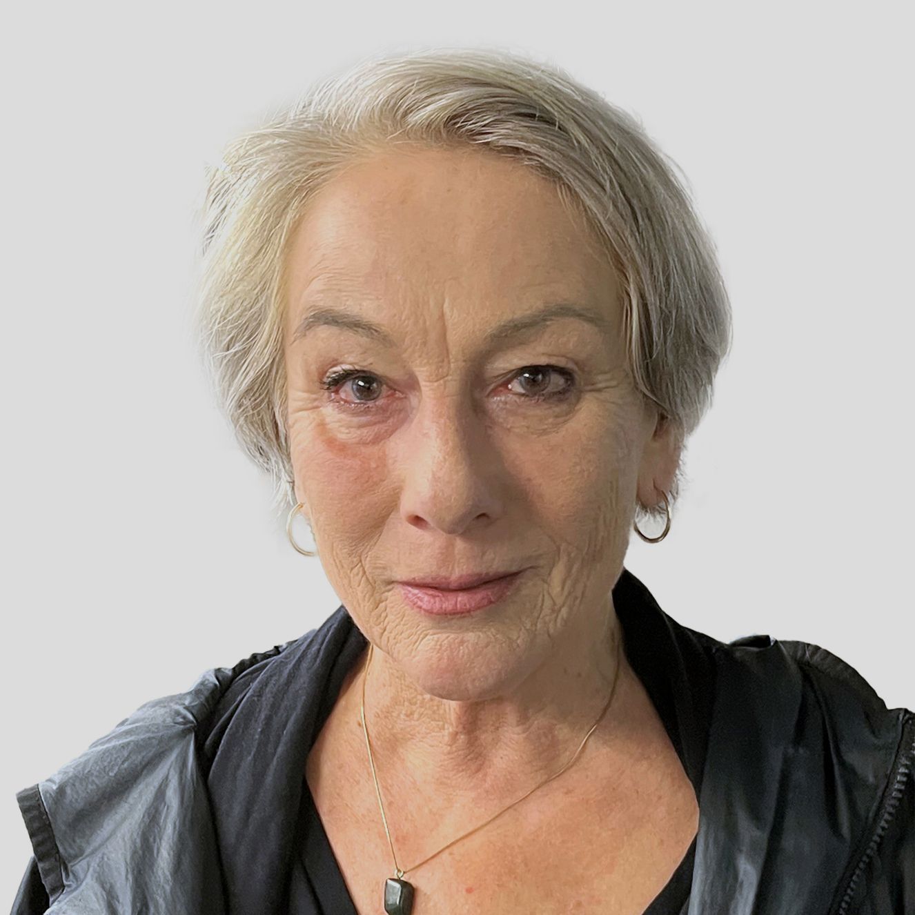 Porträtfoto von Lisi Hämmerle, Jurorin, mit kurzem grauem Haar und dunkler Kleidung vor neutralem Hintergrund.