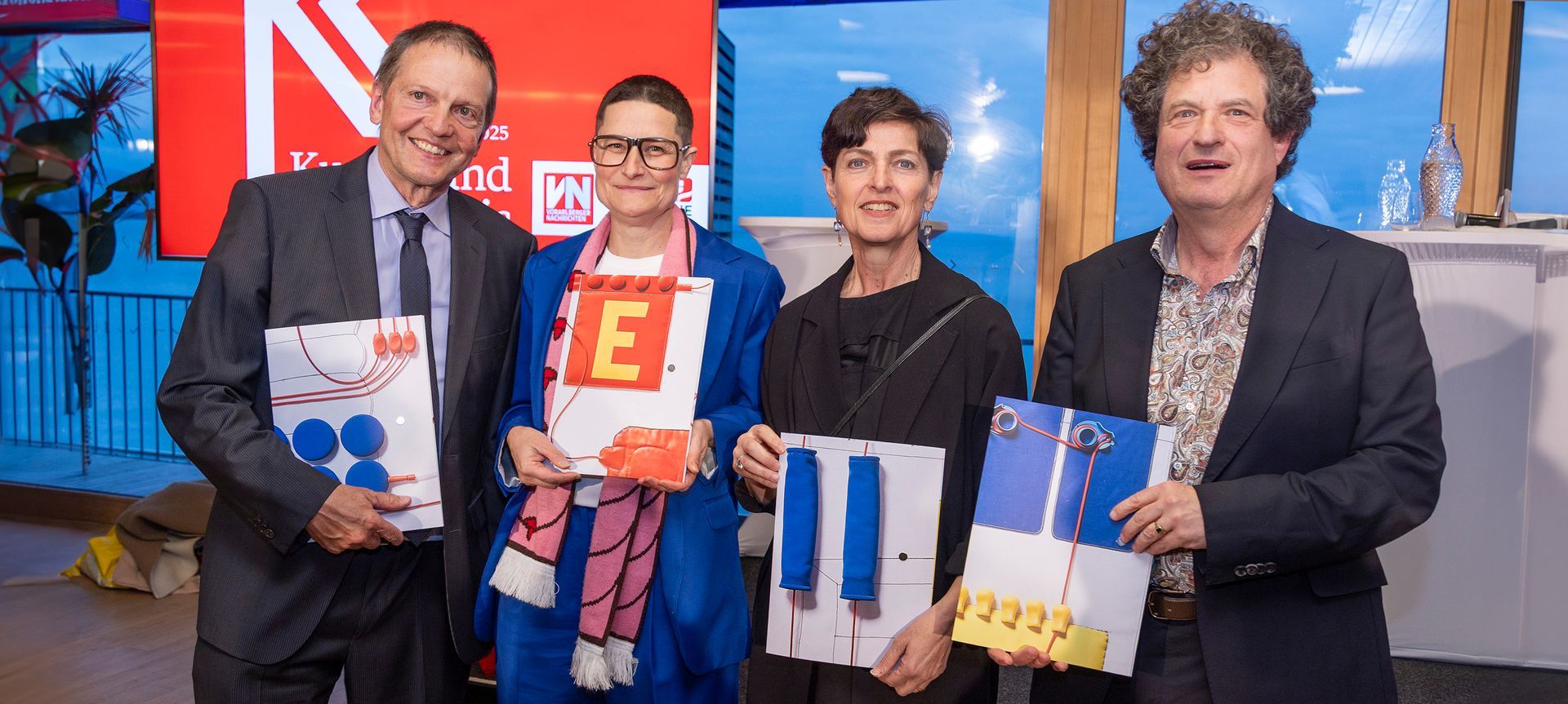 Vier Preisträger:innen des Kunst- und Kulturpreises 2025 vor rotem VN-Hintergrund