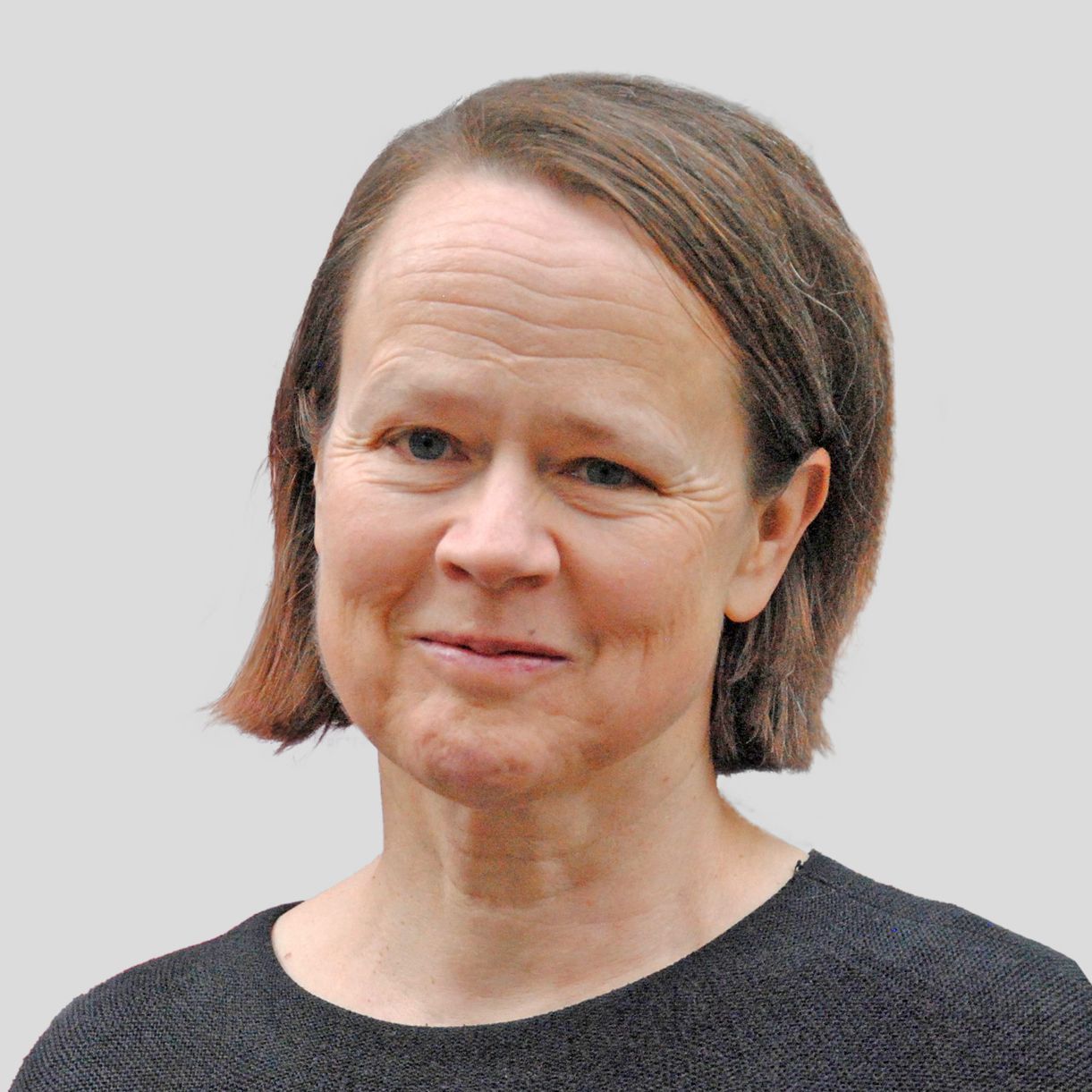 Porträtfoto von Sabine Benzer, Jurorin, mit halblangem braunem Haar und dunklem Oberteil vor neutralem Hintergrund.