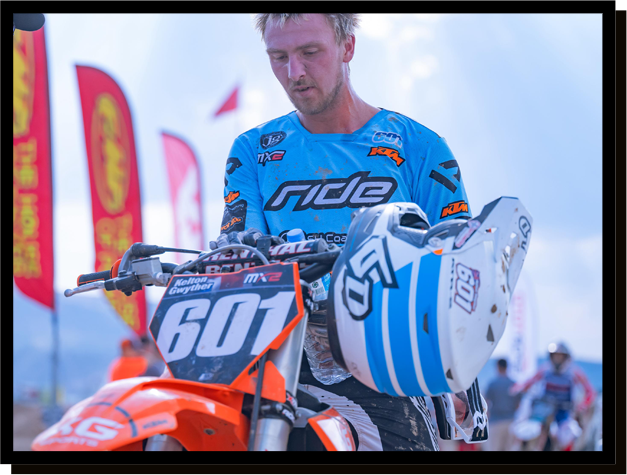 A man is standing next to a dirt bike with the number 60 on it