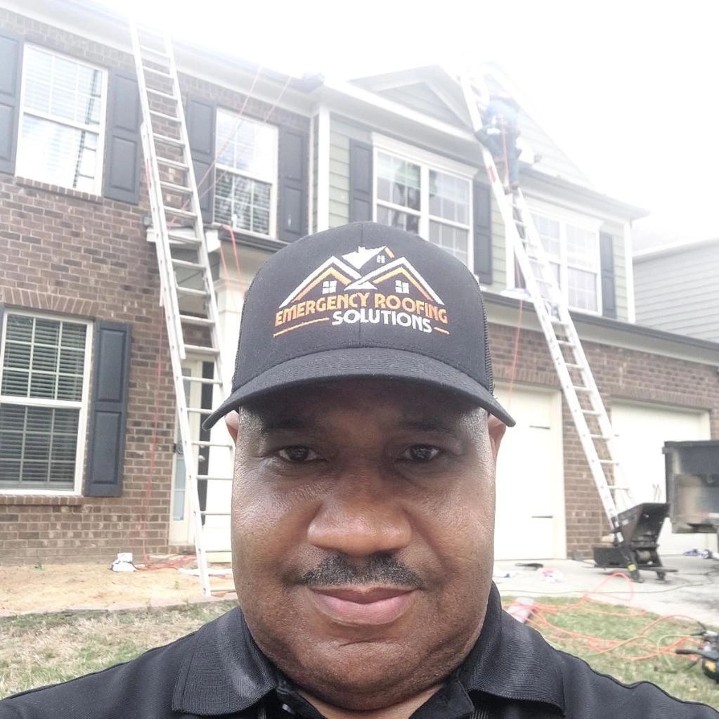 A man wearing a hat is standing in front of a house.