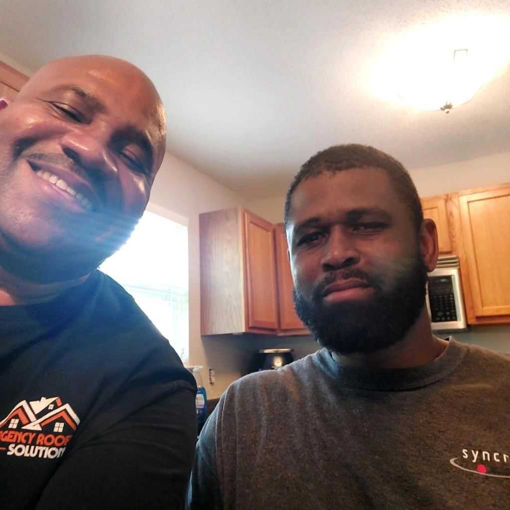 Two men posing for a picture with one wearing a shirt that says sync