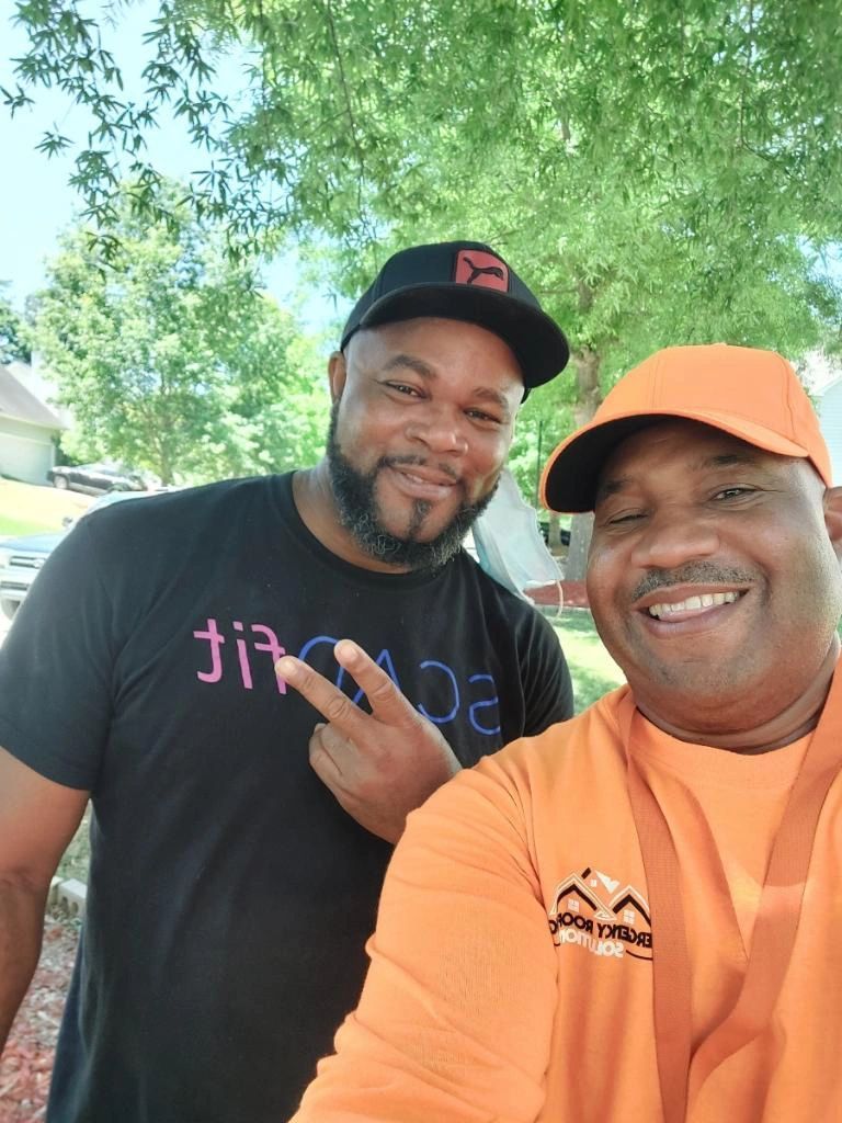 Two men are posing for a picture together and one of them is wearing an orange shirt.