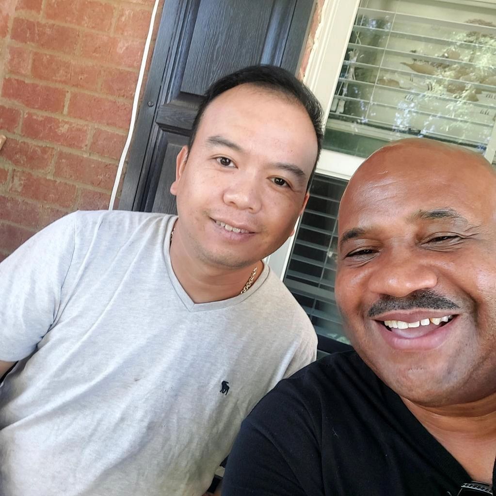 Two men are posing for a picture together and smiling for the camera.