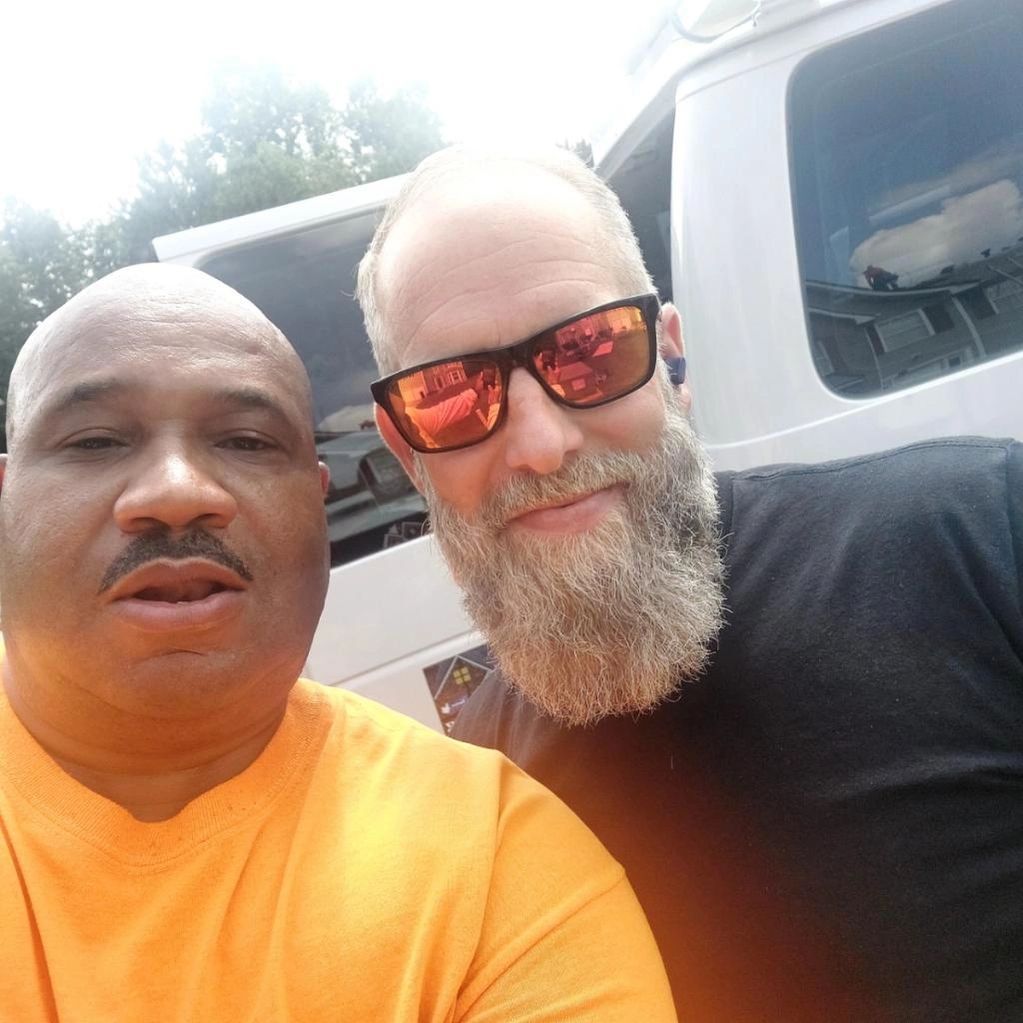 Two men with beards and sunglasses are posing for a picture.
