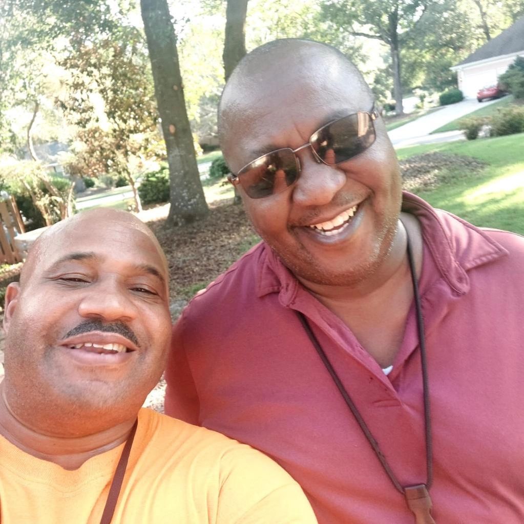 Two men are posing for a picture and one is wearing sunglasses