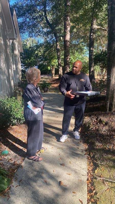 A man is standing next to an elderly woman on a sidewalk.